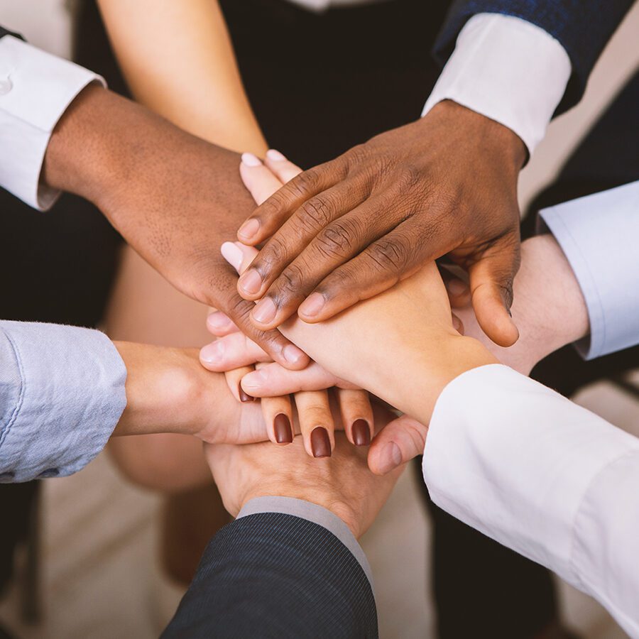 Business unity. Multiethnic corporate teame stacking hands together in office, close up